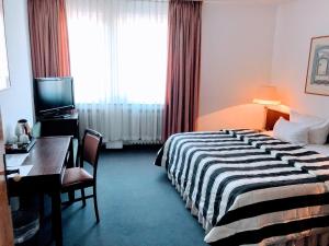 a hotel room with a bed and a desk and a television at Hotel Kölner Hof in Dormagen