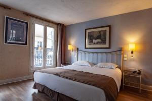 sypialnia z dużym łóżkiem i dużym oknem w obiekcie Hôtel Atlantis w Paryżu
