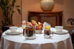 a table with a white table cloth with croissants and orange juice at Hôtel Atlantis in Paris