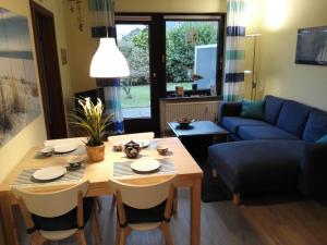 uma sala de estar com uma mesa e um sofá azul em Strandnahe Ferienwohnung Duhnen - Garten, Strandkorb, 4 Personen em Cuxhaven