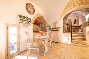 een keuken met een tafel en stoelen en een klok aan de muur bij La Neviera dell'Arco in Martina Franca