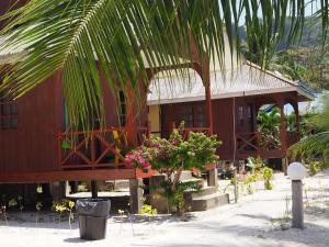 a building with a palm tree in front of it at Samudra Beach Chalet in Perhentian Islands