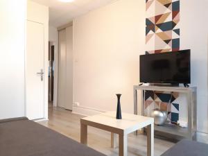 a living room with a tv and a vase on a table at Résidence des Sources in Vichy
