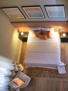 um quarto com uma grande cama branca e uma cadeira em DRAGO d' ORO SUITES em Florença