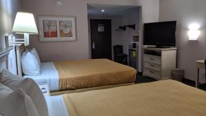 a hotel room with two beds and a flat screen tv at LAX Stadium Inn in Inglewood