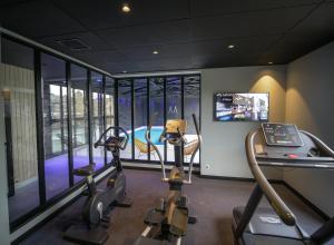 a gym with two treadmills and a gym with treadleys at Le Magic Hôtel & Spa - Centre Historique - Climatisation - Parking - Bornes de recharge in Vitré