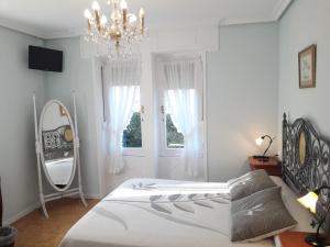 a bedroom with a bed and a mirror and a chandelier at Villa La Argentina in Luarca