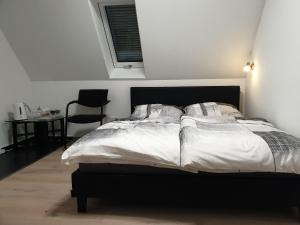 ein Schlafzimmer mit einem Bett mit weißer Bettwäsche und einem Stuhl in der Unterkunft Pension Pommernweg Ibbenbüren in Ibbenbüren