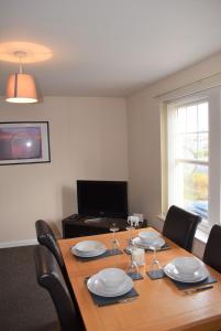 uma mesa de jantar com cadeiras e uma grande janela em Kelpies Serviced Apartments Alexander- 2 Bedrooms em Falkirk
