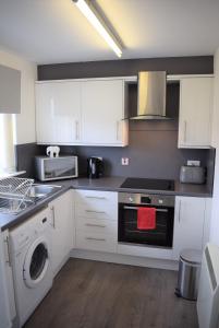 uma cozinha com armários brancos e uma máquina de lavar roupa em Kelpies Serviced Apartments Alexander- 2 Bedrooms em Falkirk