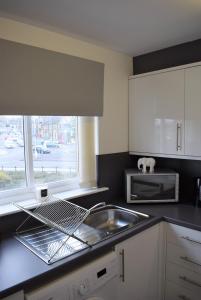 uma cozinha com um lavatório e um micro-ondas em Kelpies Serviced Apartments Alexander- 2 Bedrooms em Falkirk