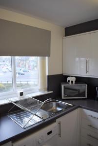 フォルカークにあるKelpies Serviced Apartments Alexander- 2 Bedroomsのシンクと電子レンジ付きのキッチン +6枚の写真