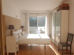 a bedroom with a white bed and a large window at Mirador del valle in Agaete