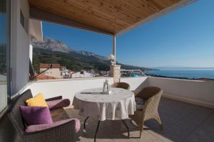 a table and chairs on a balcony with a view of the ocean at Apartment & Rooms Meri Tučepi in Tučepi