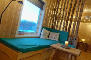 a green couch in a room with a window at Wild Caribou's Wildwood Cabin in Lakselv