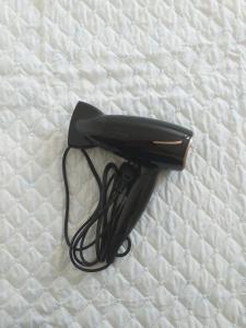 a black hair dryer sitting on a bed at Pousada Tchê Aprochega in Pelotas