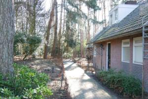 une passerelle à côté d'une maison en briques avec des arbres dans l'établissement Vakantie huisjes Duinrand Drunen, à Drunen