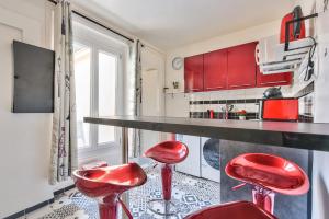 eine Küche mit roten Hockern vor einer Theke in der Unterkunft Le Cerisier - Paris Gare du Nord en 15 min - in Deuil-la-Barre