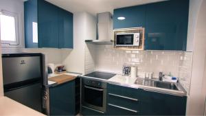 eine Küche mit blauen Schränken, einer Spüle und einer Mikrowelle in der Unterkunft The Pradise of Ana Vemar Exclusive Apartament in Playa Paraiso