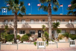 un hôtel avec des palmiers devant lui dans l'établissement Hotel Costa Blanca Rojales, à Rojales