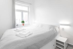 een witte slaapkamer met een wit bed en handdoeken erop bij WUCHTA WIARY Apartment in Poznań