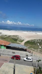 two cars parked in a parking lot next to a beach at Apartamento Sophia 1 in Arraial do Cabo