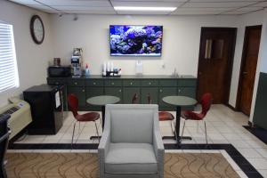 a waiting room with two tables and a tv on the wall at VIP Inn and Suites in Huntsville