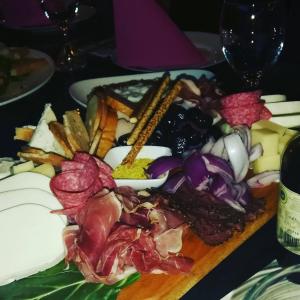 a plate of food with meats and vegetables on a table at Hotel Panorama city in Delčevo