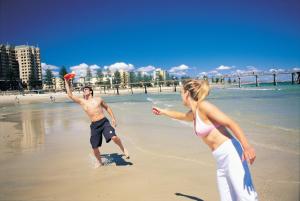 Adelaide的住宿－恩塞納達套房汽車旅館，一名男子和女子在海滩上玩飞盘