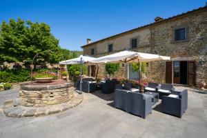 a patio with chairs and umbrellas in front of a building at Villa Borgo San Pietro in Cortona