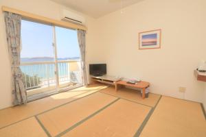 a living room with a large window and a television at Tokashiku Marine Villege in Tokashiki