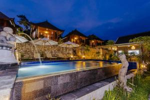 a villa with a swimming pool at night at Sunday Huts Lembongan in Nusa Lembongan