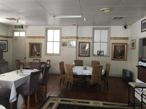 une salle à manger avec des tables, des chaises et des peintures sur les murs dans l'établissement Club Boutique Hotel Cunnamulla, à Cunnamulla
