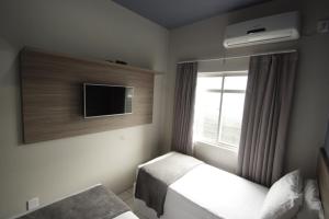 a bedroom with two beds and a tv and a window at Kennedy Slim Hotel in São José