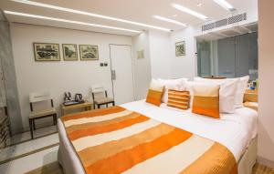 um quarto com uma cama grande com almofadas laranja e branca em Hotel Bawa Continental em Mumbai