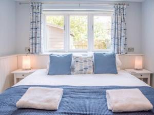 a bedroom with a bed with blue pillows and a window at Suilven Holiday Let in Aldeburgh