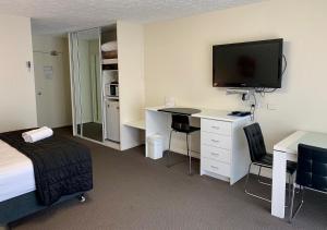 a hotel room with a bed, desk and television at Outrigger Burleigh in Gold Coast
