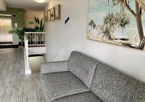 uma sala de estar com um sofá cinzento contra uma parede em Outrigger Burleigh em Gold Coast