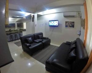 sala de estar con muebles de cuero negro y TV en Sleepadz - Capsule Beds Dormitel in Magsaysay Ave Naga, en Naga