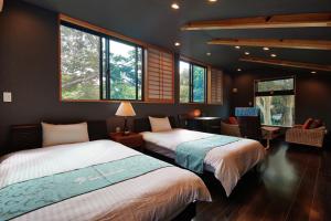 a bedroom with two beds and windows and a desk at Private Villa Churaya Yaedake Bettei with 500sqm garden in Motobu