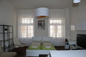 - un salon avec une table et 2 fenêtres dans l'établissement Arany Janos Apartman, à Budapest