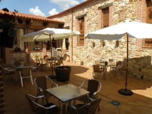 un patio con mesas, sillas y sombrillas en Hotel Rural VII Carreras by Vivere Stays, en San Pedro de Rozados