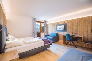 a bedroom with a bed and a desk and a chair at Hotel Kranebitt B&B in Bressanone +37 photos