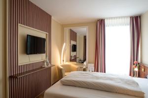 a hotel room with a bed and a television on a wall at Hotel Primula in Troisdorf