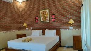 a bedroom with a white bed with a brick wall at Villa Eliska Sari Sumberkima in Pemuteran