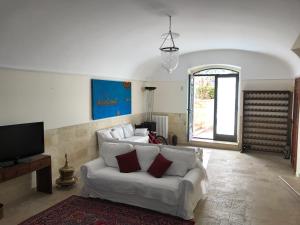 a living room with a white couch and a tv at Giardini 82 B&B in Gravina in Puglia