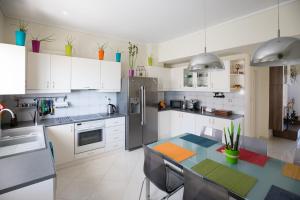 a kitchen with white cabinets and a table in it at Groovy & Cozy APT with Private Seaview Rooftop Terrace in Rhodes Town