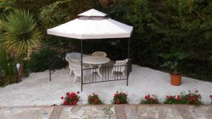a table and chairs under a white umbrella at B&B Pian del Lago in Caltanissetta
