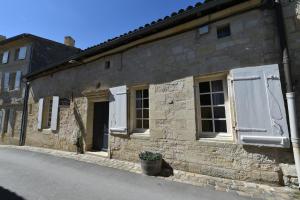an old stone building with white shutters on a street at logis-des-cordeliers in Saint-Émilion