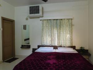 ein Schlafzimmer mit einem lila Bett und einem Fenster in der Unterkunft Shri Gita Hotel in Raipur